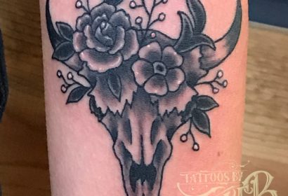 Black and grey flowers and cow skull tattoo
