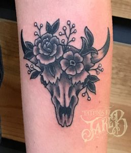 Black and grey flowers and cow skull tattoo